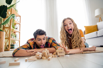 Photo of charming crazy excited people lying floor playing jenda game puzzle pile stack wooden...