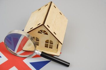 Real estate in UK concept. Wooden house model under magnifying glass on British flag. Copy space...