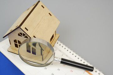 House model under magnifying glass on calendar page, room for text. Find house for rent and buy...
