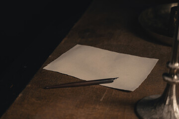 Ink pen and blank sheet on antique wooden desk. An empty white page with an old calligraphy ink pen...