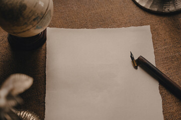 Old calligraphy ink pen are on the old-fashioned table. Ink pen and blank sheet on antique wooden...