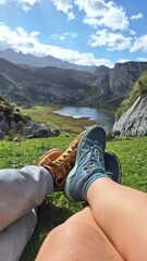 couple of people showing their feet in front of the lake and the mountains
