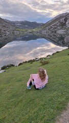 woman sitting on a grass in front of lake