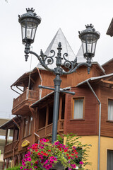 Lantern with flower pot flowerbed. Old street lamp. A pole with a glass incandescent lampshade....