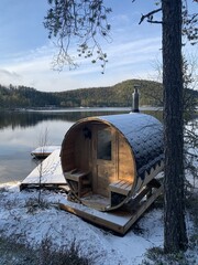 round wooden sauna on a calm lake