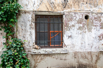 Close dirty rustic aged window in old house on the street.