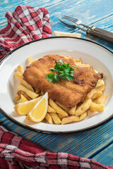 A piece of fried cod with fries on a plate.