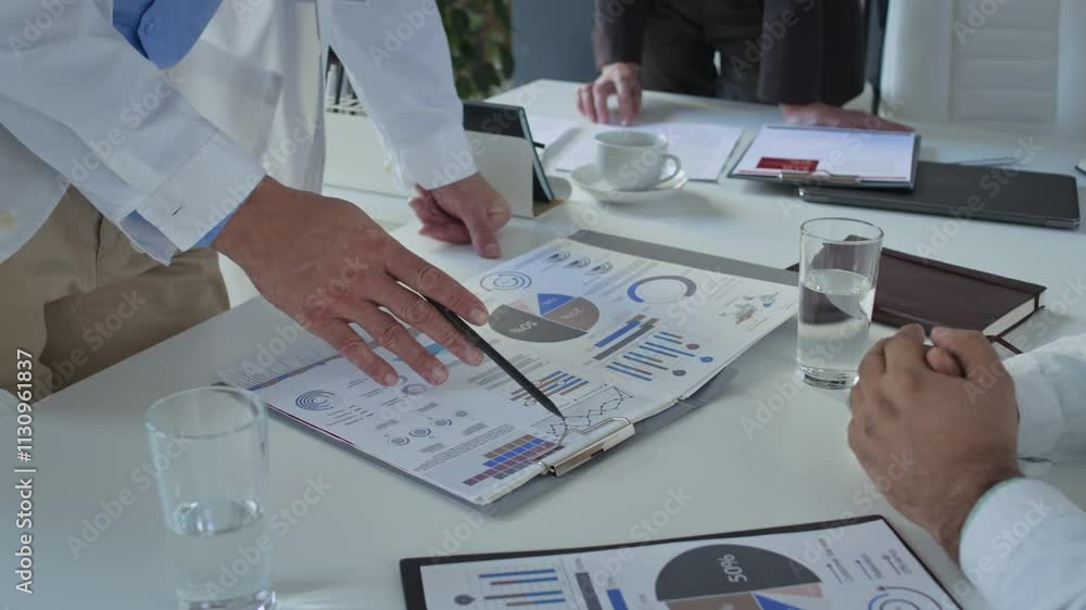 Poster close up view of hands of unrecognizable doctor in medical coat pointing at detailed charts on clipb