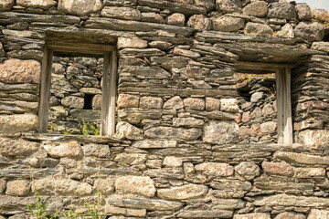 Old stone ruins with empty windows in a historical site, partially covered in greenery