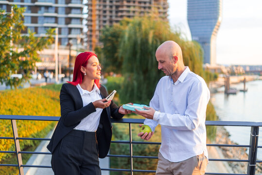 Business people having lunch break eating sandwiches outdoors near river