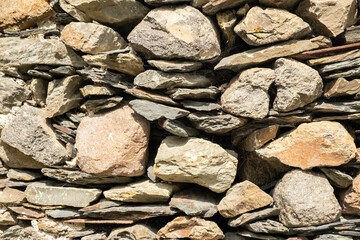 Stone wall made of various shapes and sizes of rocks in a rustic style found in a countryside...