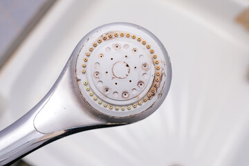 Silver shower head with limescales that should be cleaned. Calcified shower due to hard water. Calcium mineral buildup.