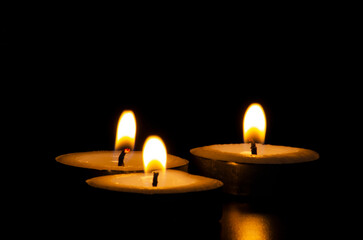 Three candles shining in the dark with customizable space for message, text or ideas. Copy space and candles concept