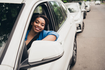 Young woman enjoying a sunny day in the city while driving a car