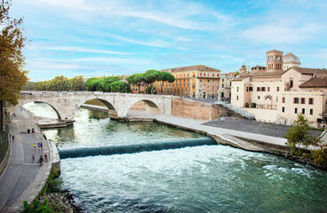 The water of the Tiber River streams beneath the Ponte Cestio (Cestian Bridge) near Tiber Island, as local people walk and bike on a summer afternoon in Trastevere, Rome, Italy.