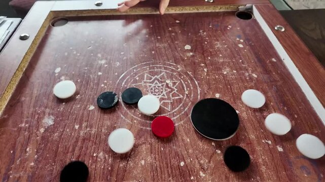 Slow-motion of person's hand while playing Carrom Board