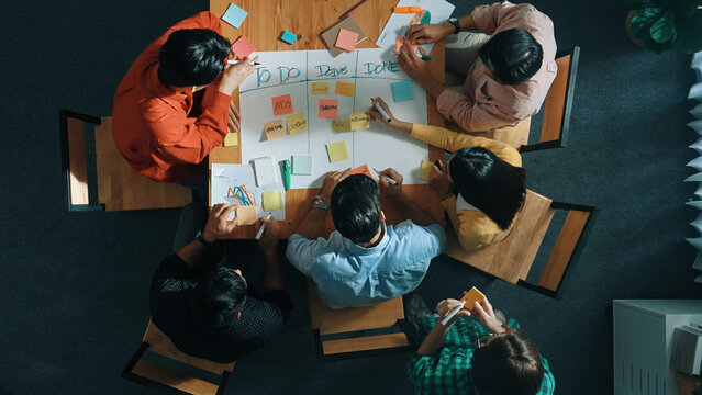 Top view of people writing and making scrum task board while writing marketing and planning strategy at colorful sticky notes. Smart team manage work performance by using kanaban board. Convocation.