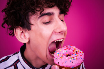 Diet and healthy lifestyle. Funny curly guy eats a donut.