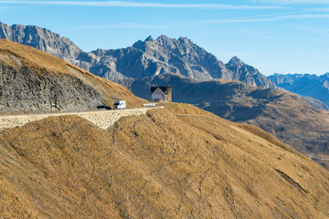 caravan on the mountain road with a rocks and building in the background