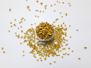 Gold color masterbatch granules in cup and isolated on white background,color pigment carrier polymer in plastic industry.Perfect for plastic company catalog design.