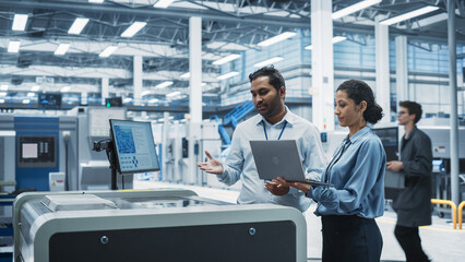 Indian Male Industrial Engineer And Hispanic Female Manager Using Laptop And Talking At Electronics...