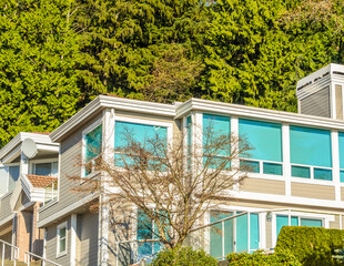 Top of grey luxury house with shingle roof, red and yellow trees and nice windows in Summer in...