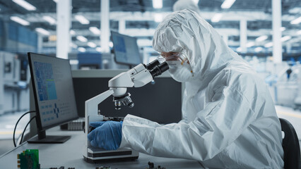 Two Scientists In Sterile Suites At Electronics Factory: Engineer Using Microscope And Desktop...