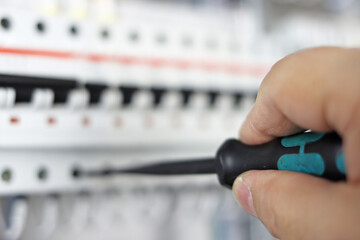 Installation of mounting wires in an electrical switchboard using a screwdriver.