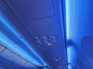 A sleek and modern airplane interior with blue LED lighting and visible ventilation systems, ideal for designs related to air travel or aviation interiors.