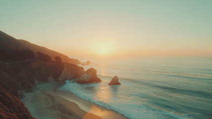 Obraz premium Sunset over a rocky coastal cliff with calm waves and sandy beach.