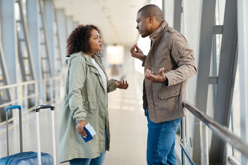 African American Couple arguing at airport terminal, forgot some things at home, side view