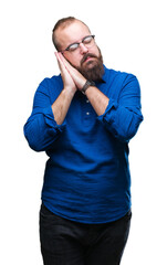 Young caucasian hipster man wearing glasses over isolated background sleeping tired dreaming and posing with hands together while smiling with closed eyes.