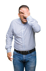 Fototapeta premium Middle age arab business man over isolated background peeking in shock covering face and eyes with hand, looking through fingers with embarrassed expression.