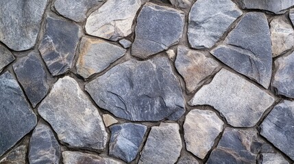 Obraz premium Textured stone wall surface with irregularly shaped slate stones in shades of gray arranged in a natural pattern for design backgrounds