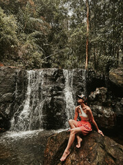 A young woman sits on a stone at the Suoi Tranh waterfall