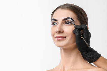 Naklejka premium Young woman undergoing henna eyebrows dyeing on light background, closeup. Space for text