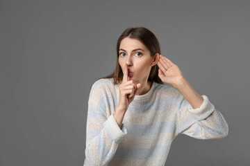 Woman showing hand to ear gesture on grey background, space for text