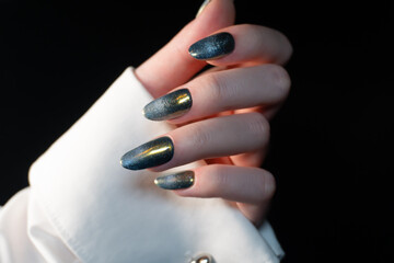 Contemporary manicure with a magnetic effect of cat-eye polish on a black background, shimmering...
