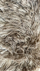 Fototapeta premium Close-up of soft beige shaggy fabric texture, showing intricate fibers and depth. Ideal for concepts related to comfort, interior design, upholstery, or cozy home decor themes.
