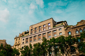 Fototapeta premium Classical Urban Building Surrounded by Green Trees and Blue Sky