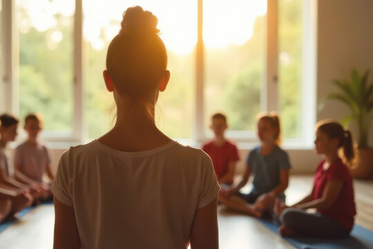 Yoga instructor a yoga class for group of childrens in bright studio. Concept of wellness, junior fitness and yoga training