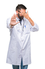 Adult hispanic doctor man over isolated background covering eyes with hands and doing stop gesture...