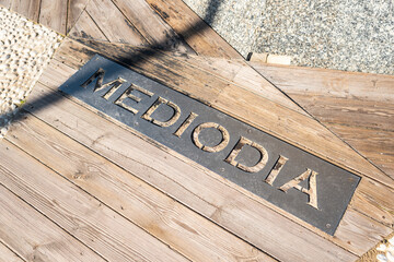 Wooden walkway with Mediodía wind direction plaque in Tarifa, Spain