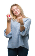 Young caucasian woman eating sweet cupcake over isolated background happy with big smile doing ok...