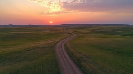 Fototapeta premium Sunset Prairie Road Aerial View of Winding Dirt Path Across Rolling Hills at Golden Hour