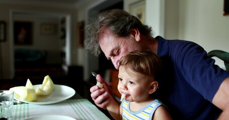 Baby spitting food out, toddler spits fruit on grand-father lap