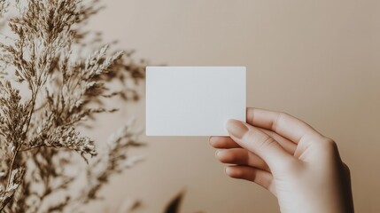 Obraz premium Minimalist hand holding empty card with natural boho style arrangement