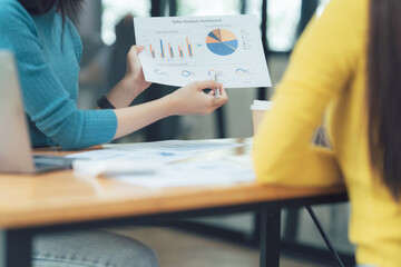 Businesswomen Collaborate: Two professional women discuss financial data, charts, graphs, and...