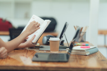 Planning the Day: A woman's hands meticulously reviewing her planner amidst a workspace of...