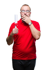 Young hipster man wearing glasses and holding degree over isolated background cover mouth with hand shocked with shame for mistake, expression of fear, scared in silence, secret concept